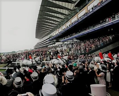 a crowd of well-dressed people applauding horses at a racetrack